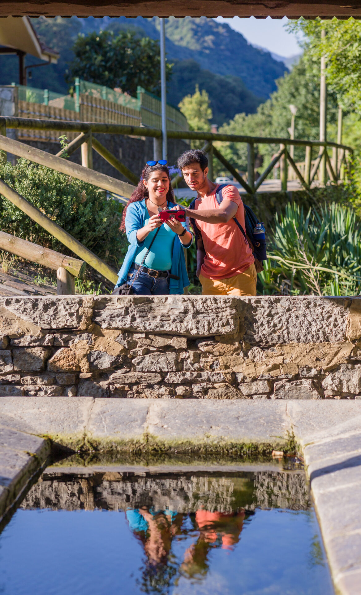 Eco friendly ancient lavoir washhouse. Mixed race mid couple photographing with smartphone.